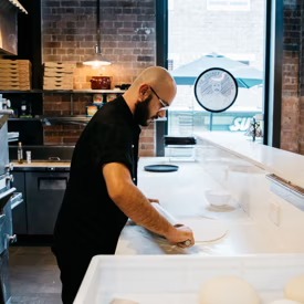 Chef hand-preparing fresh pizza dough at The Grumpy Italian Leichhardt kitchen